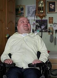 Janusz Świtaj siedzi na wózku w swoim pokoju