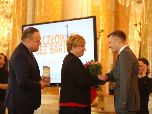 Agnieszka Sprycha i Jarosław Duda wręczają statuetkę i kwiaty Mariuszowi Kędzierskiemu