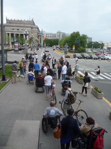 tłum osób przechodzi pod pałacem