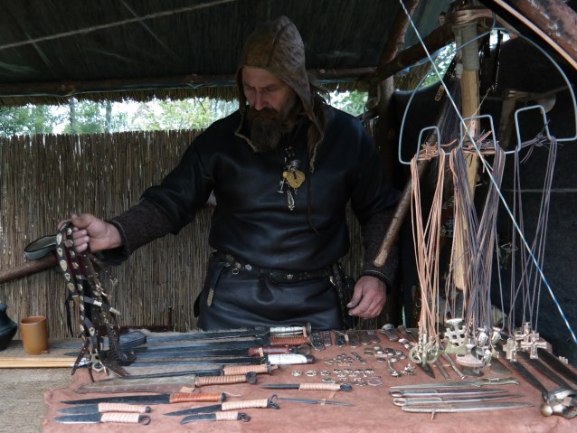 mężczyzna pokazuje noże, rzemyki i broń używane przez Słowian