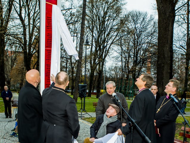 kilku mężczyzn odsłania biało-czerwony Pomnik Tolerancji - 