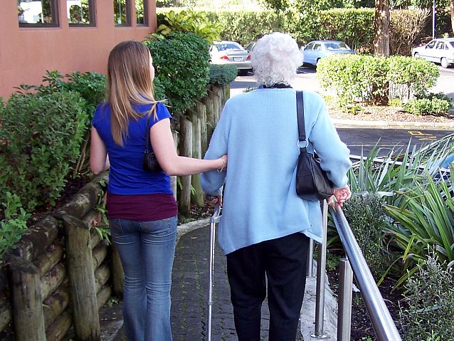 Młoda kobieta trzyma pod rękę starszą panią podczas spaceru