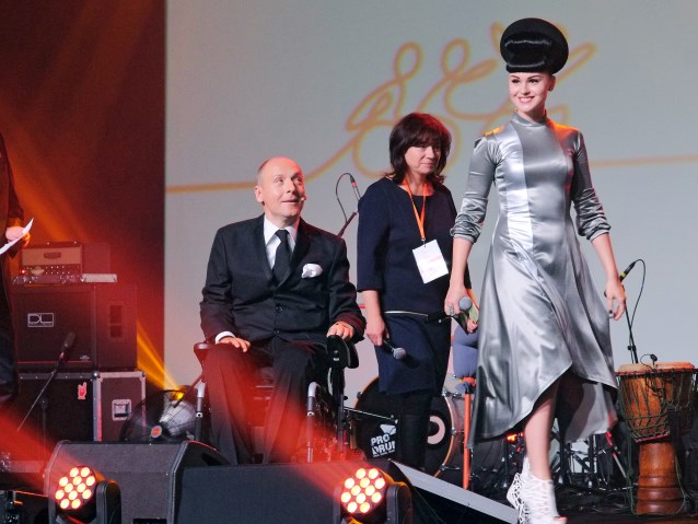 Viktoria Modesta idzie po scenie, za nią tłumaczka, Piotr Pawłowski i Artur Andrus. 