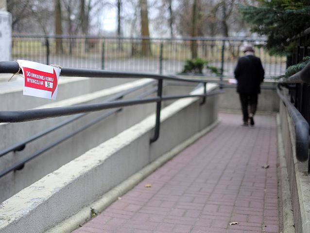 Starsza osoba schodzi po pochylni, na pierwszym planie strzałka z napisem: do obwodowej komisji wyborczej nr 96