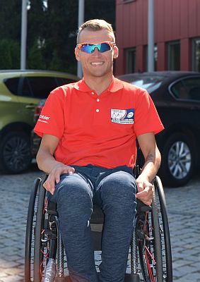 Uśmiechnięty Rafał Mikołajczyk siedzi na wózku