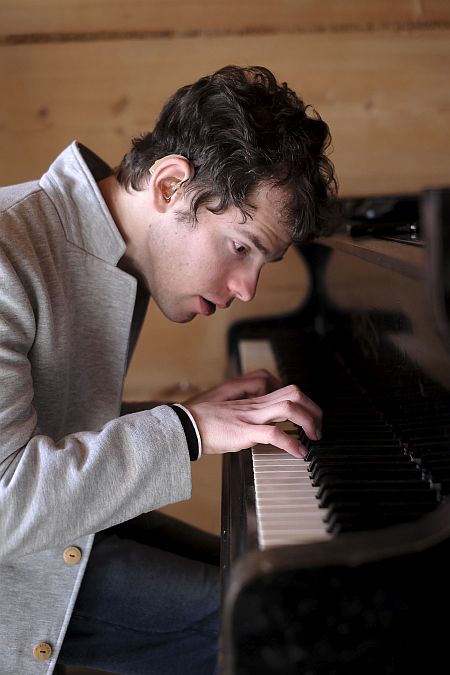 Grzegorz Płonka gra na fortepianie, nachylony nad klawiaturą
