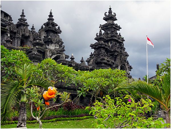 Pluszowy pomarańczowy kameleon siedzi na drzewie wśród starożytnych budowli na Bali