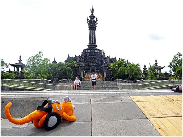 Pluszowa maskotka pomarańczowego kameleona na tle azjatyckiej świątyni