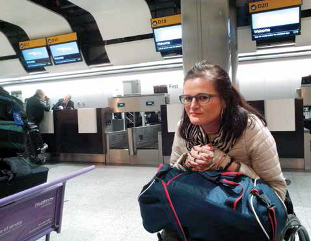 Julita oparta o torbę na kolanach poirytowana czeka na asystenta na lotnisku Heathrow