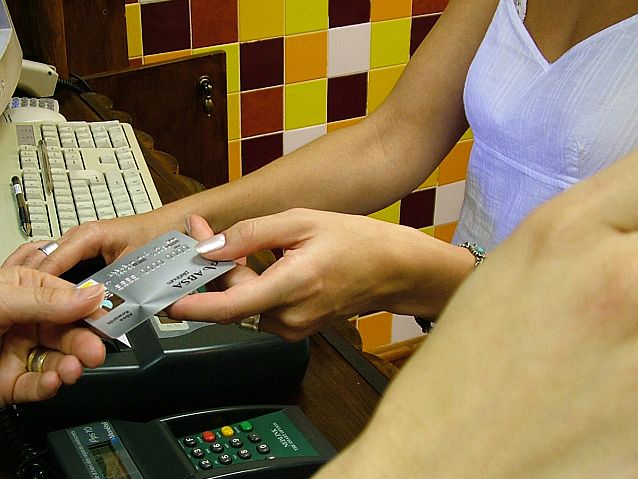 Kobieta przekazuje innej osobie kartę kredytową podczas wizyty w sklepie