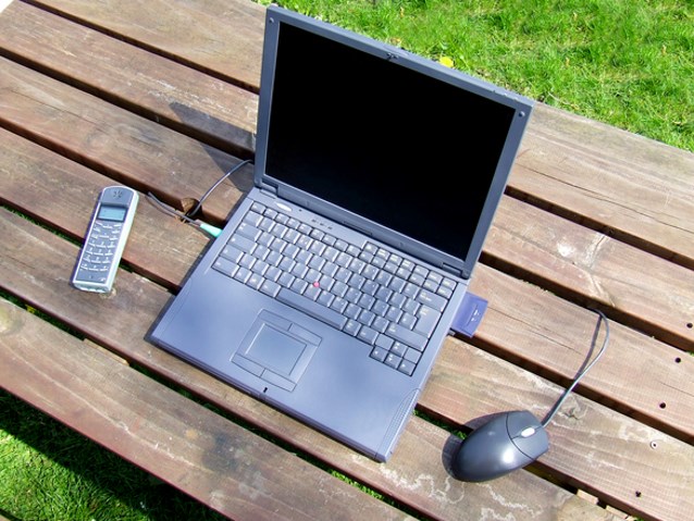 laptop leży na drewnianym stoliku w ogrodzie