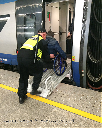 Ochroniarz pcha osobę na wózku po podjeździe do wejścia do wagonu pociągu