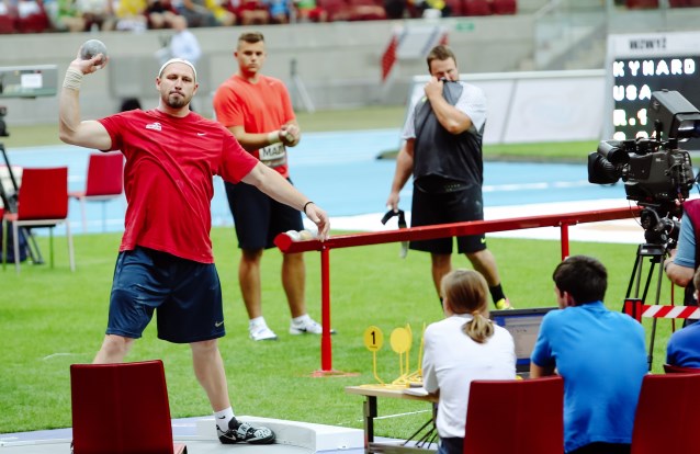 Tomasz Majewski trzyma kulę w dłoni, w tle kibicie