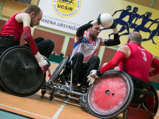 rugbysta podaje piłkę, z dwóch stron przeszkadzają mu zawodnicy innej drużyny