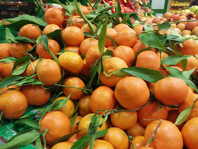Leżące na straganie świeże pomarańcze z liśćmi