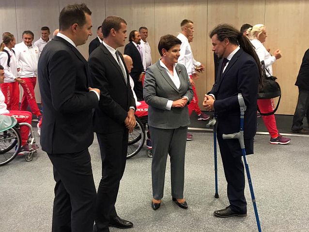 Łukasz Szeliga rozmawia z premier Beatą Szydło, obok stoi m.in. minister sportu Witold Bańka, w tle paraolimpijczycy