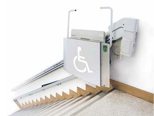 przy schodach zamontowane urządzenie do przewozu na górę osób z niepełnosprawnością