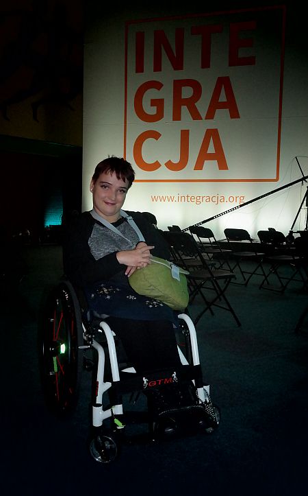 Katarzyna Wasiak siedzi na wózku, za nią napis Integracja
