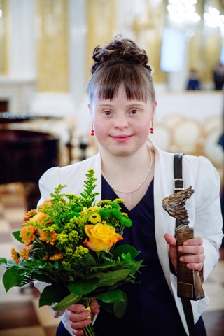 Uśmiechnięta Joanna Rogozińska ze statuetką i z kwiatami