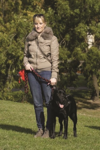 Dorota Ziental stoi na trawie z psem przewodnikiem