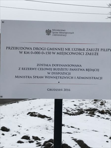 Tablica z napisem: przebudowa drogi gminnej w miejscowości Załuże dofinansowana z rezerwy celowej budżetu państwa będącej w dyspozycji ministra spraw wewnętrznych i administracji, grudzień 2016