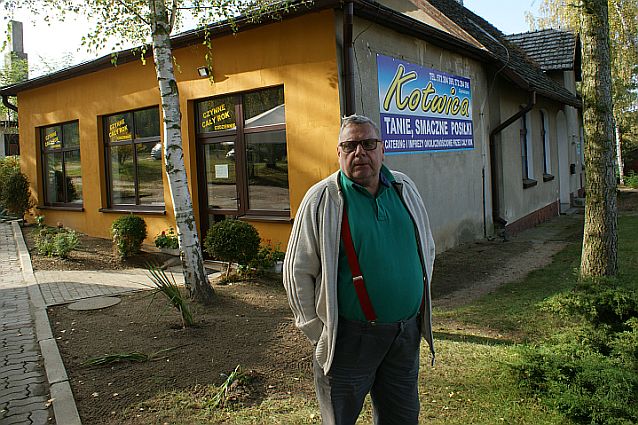Mężczyzna stoi przed niewielkim budynkiem z napisem Kotwica: tanie, smaczne posiłki