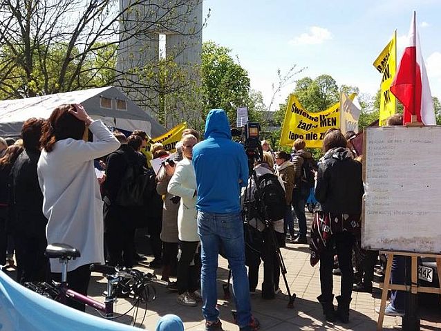 Grupa protestujących osób i przedstawiciele mediów z kamerami