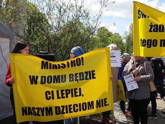 Manifestanci trzymają transparenty. Na jednym z nich napis: Ministro! W domu będzie ci lepiej, naszym dzieciom nie.