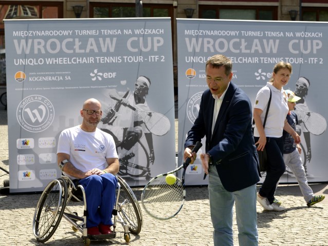 tenisista na wózku, obok niego mężczyzna sprawny odbija lotkę rakietą