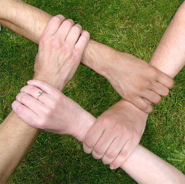 Cztery ręce trzymające się wzajemnie za przedramiona