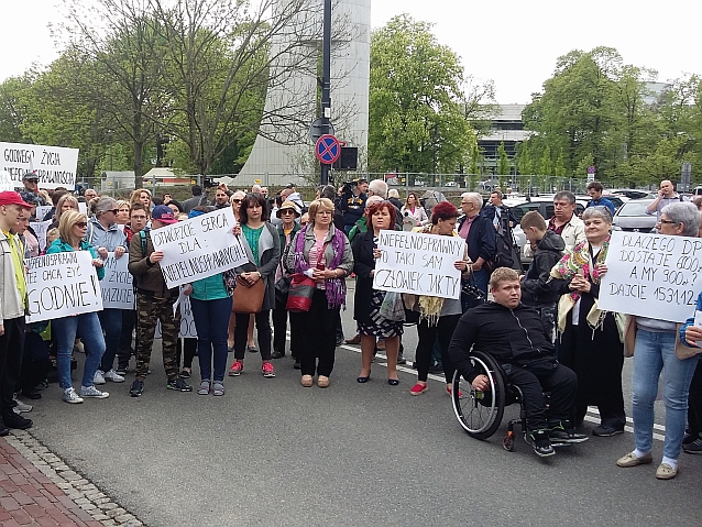 Manifestujący pod sejmem trzymają transparenty z napisami m.in. Niepełnosprawni też chcą żyć godnie, Otwórzcie serca dla niepełnosprawnych