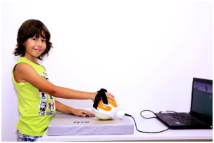 Chłopiec z ręką przypiętą do niewielkiego kulistego urządzenia, z którego kabel prowadzi do laptopa