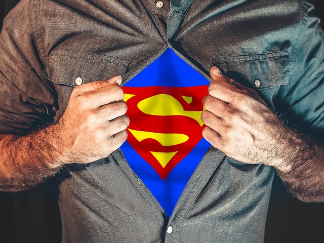 mężczyzna rozchyla koszulę, pod którą widać literę S, logo Supermana