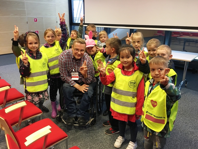 Łukasz Bednarski na wózku pozuje razem z dziećmu - uczestnikami szkolenia do zdjęcia