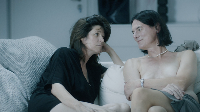 z lewej strony Laura, z prawej transseksualistka bez bluzki. Bohaterowie siedzą obok siebie na sofie i patrzą sobie w oczy