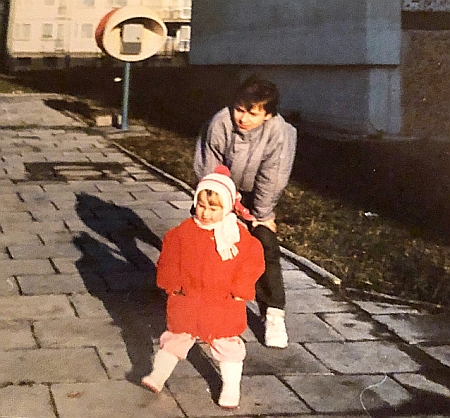 Młody chłopiec stoi na chodniku za swoją małą siostrzyczką