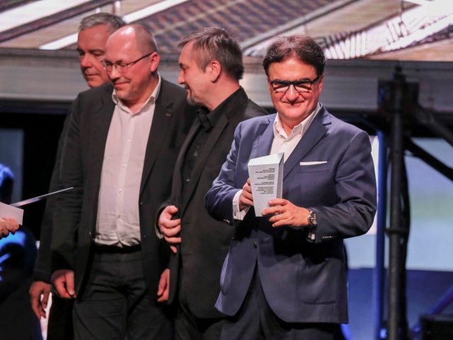 przedstawiciele Praskiego Centrum Koneser na scenie 4 mężczyzn jeden z nich trzyma nagrodę