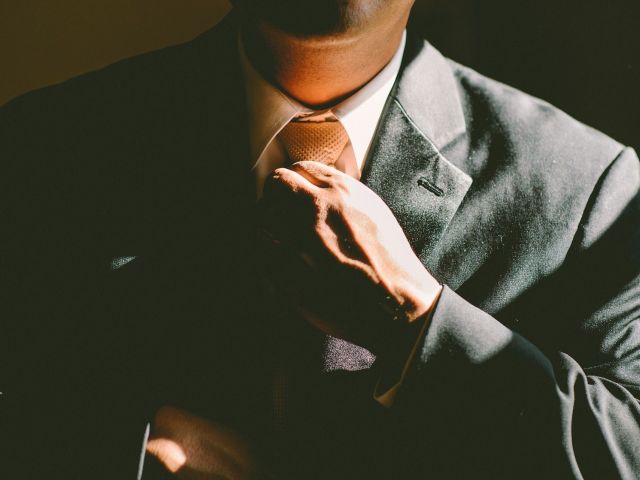 mężczyzna w garniturze poluzowuje ręką krawat