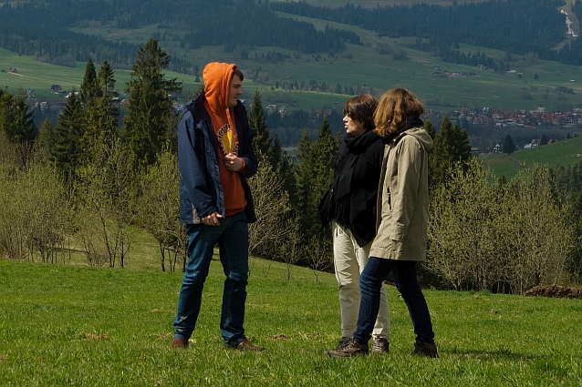 Mężczyzna i dwie kobiety stoją i rozmawiają na zboczu wzgórza