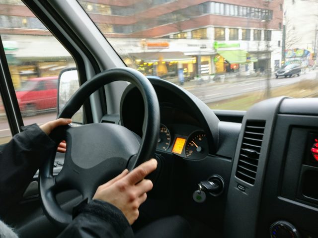 ręce na kierownicy samochodu w czasie jazdy przez miasto
