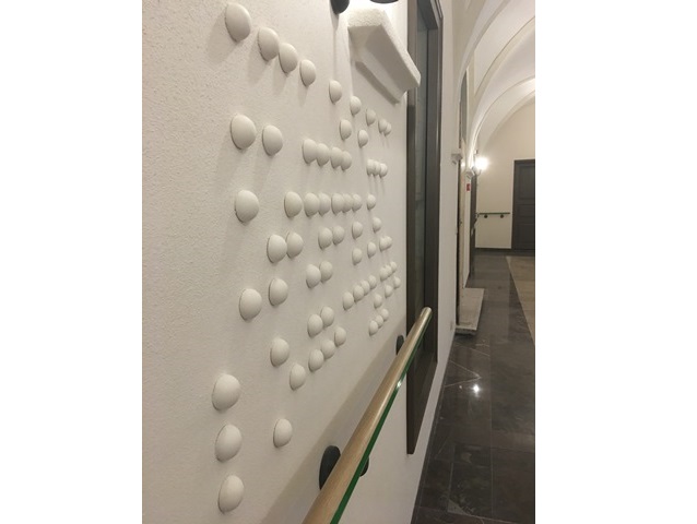 biała ściana na korytarzu z guzikami brajla