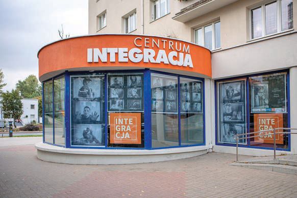 Połączona z wysokim budynkiem parterowa rotunda z napisem Centrum Integracja. W oknach wystawione czarno-białe zdjęcia