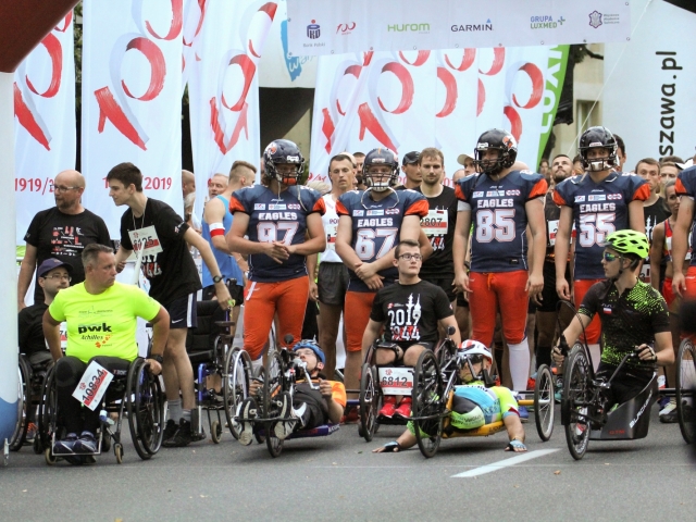 grupa sportowcow na wózkach, hanbikach i pełnosprawnych w ochraniaczach na głowach