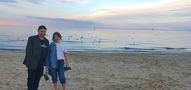 Stanisław Kmiecik pozuje do zdjęcia z młodą dziewczyną na tle morza