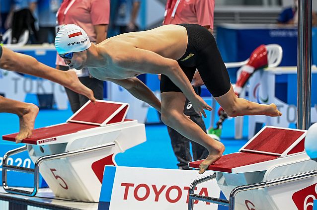 Igor Hrehorowicz skacze do basenu ze słupka podczas startu wyścigu pływackiego w Tokio