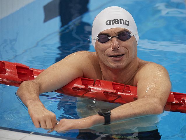 Pływak Jacek Czech w czepku na krawędzi basenu uśmiecha się do fotografa
