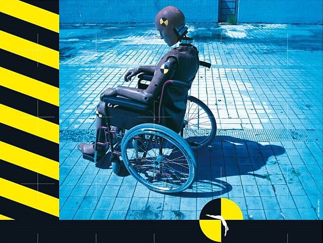 Plakat ze zdjęciem manekina ze złamanym karkiem siedzącego na wózku ustawionym w pustym basenie
