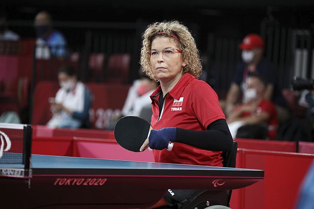 Dorota Bucław na wózku przy stole do tenisa stołowego z rakietką w dłoni