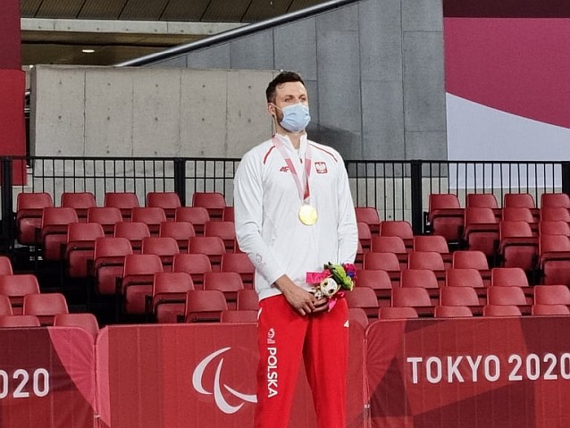 Patryk Chojnowski stoi na podium ze złotym medalem na szyi