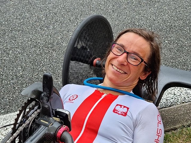 Uśmiechnięta Renata Kałuża leży na ręcznym rowerze